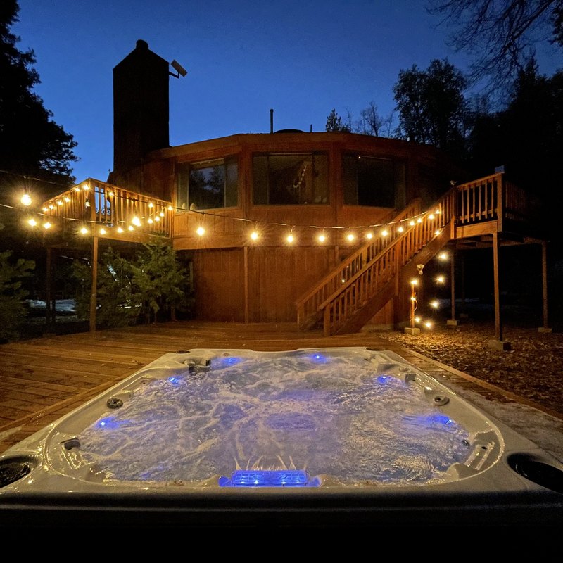 Hot tub on the deck at dusk beneath string lights